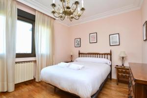 a bedroom with a large bed and a chandelier at 210A Casa Linares Amplia casa en Villaviciosa in Cadamancio