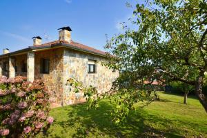 a stone house with a tree and flowers in front of it at 210A Casa Linares Amplia casa en Villaviciosa in Cadamancio