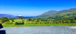 a bench sitting in the grass with an umbrella at Sky View Cabin in Ardaghy