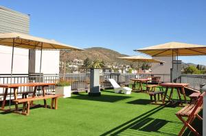 eine Terrasse mit Tischen und Sonnenschirmen auf dem Dach in der Unterkunft DPto Carlos Paz in Villa Carlos Paz