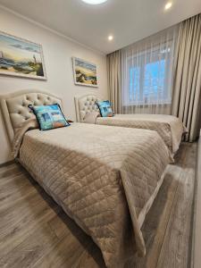 a bedroom with two beds and a window at E.D. Luxury Apartaments in Šiauliai