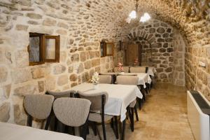 a dining room with stone walls and tables and chairs at Kadimhan konağı otel in Mardin