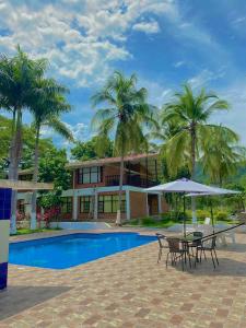 a house with a pool and a table with an umbrella at Casa campestre el samán in Utica