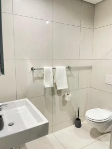 a white bathroom with a sink and a toilet at ProAvia Apartments and Hotel in Windhoek