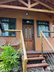 une maison avec une porte en bois et des escaliers devant dans l'établissement Chalé Santo Antônio do Pinhal, à Santo Antônio do Pinhal