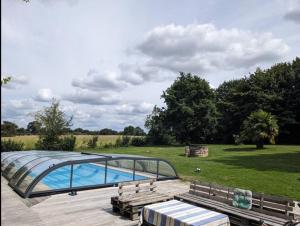 ein Swimmingpool mit Bänken auf einem Deck in der Unterkunft La Lectais in Romille