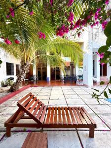 a wooden bench in front of a building with pink flowers at Incredible Loft with pool in Chuburná de Hidalgo