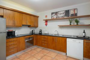 una cucina con mobili in legno e un frigorifero bianco di Casa Jardim Celeste a Seixal