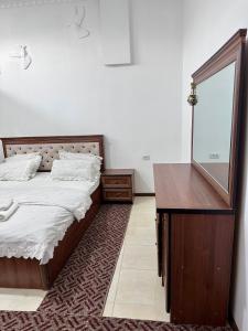 a bedroom with a bed and a dresser and a mirror at The Homely Stay in Bukhara