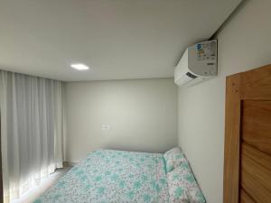 a small bedroom with a bed and a air conditioner at Linda casa a 150mts da Praia in Camaçari +10 photos