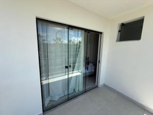 a glass shower in a white room with a window at Linda casa a 150mts da Praia in Camaçari