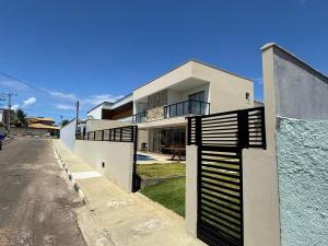 a white house with a black gate on a street at Linda casa a 150mts da Praia in Camaçari