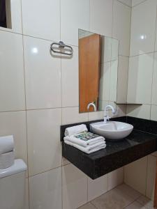 un baño con lavabo y espejo en Chalé Hotel, en Piratininga 7 fotos más