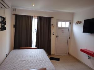 a bedroom with a bed and a window and a door at Las ruinas 1 in Carhué +1 photo