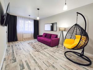 - un salon avec un canapé violet et une balançoire dans l'établissement Арбат в Золотом квадрате двухкомнатная стильная в центре 25, à Almaty