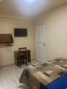 a bedroom with a bed and a desk and a television at Quarto Casal em Belém in Belém