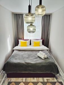 une chambre avec un lit avec des oreillers jaunes et des lustres dans l'établissement Арбат в Золотом квадрате двухкомнатная стильная в центре 25, à Almaty