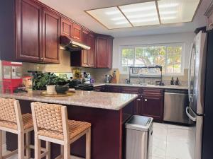 a kitchen with wooden cabinets and a counter with stools at Spacious 4B2B HOUSE DTLA & Disney Office Gym in Hacienda Heights