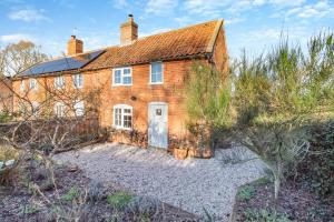 an old brick house with a white door at Valentine Cottage in Snape