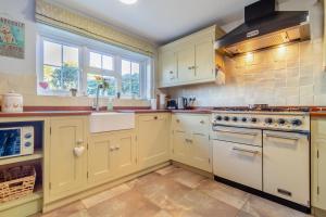 a kitchen with yellow cabinets and white appliances at Valentine Cottage in Snape