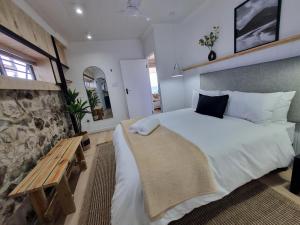 een slaapkamer met een groot bed en een houten bank bij Petra in Bettyʼs Bay +32 foto's