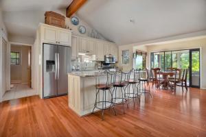 Una cocina con gabinetes blancos y taburetes de bar. en Beaver Lake Oasis - Backyard Lake Access - 6 beds, en Lowell