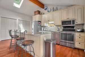 Una cocina con gabinetes blancos y taburetes de bar. en Beaver Lake Oasis - Backyard Lake Access - 6 beds, en Lowell