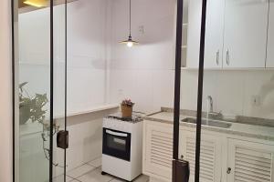 a kitchen with white cabinets and a sink and a stove at Costa Family-Casa Costa (downtown Santa Rita) in Santa Rita do Sapucaí