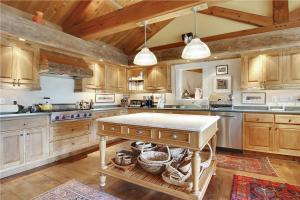 a large kitchen with wooden cabinets and a table at Soupcon: 4 br, fireplaces, game room, sauna, hot tub, views in Stowe