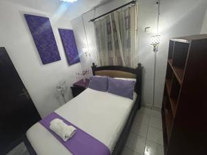 a small bedroom with a bed with purple pillows at The Fair Heavens Suite One bedroom self contained in Freetown
