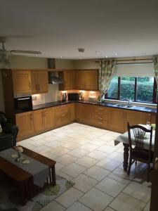 a kitchen with wooden cabinets and a table and a dining room at Meadowville Self-Catering in Cushendall