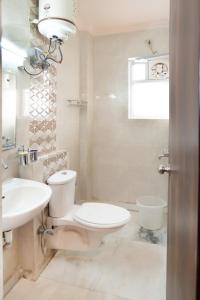 a white bathroom with a toilet and a sink at Fitel in Gurgaon