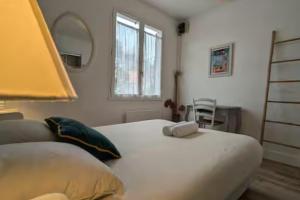 ein Schlafzimmer mit einem großen weißen Bett und einem Spiegel in der Unterkunft La Maison Brévinoise, Pines in Saint-Brévin-lʼOcéan