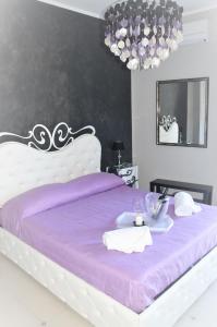 Una cama blanca con sábanas moradas y una bandeja de comida. en B&B A Due Passi Dal Mare, en Taormina