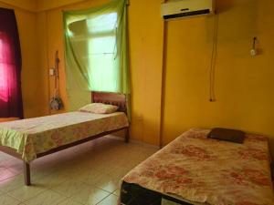 two beds in a room with yellow walls and a window at Aconchego benevides Barcelona in Benevides