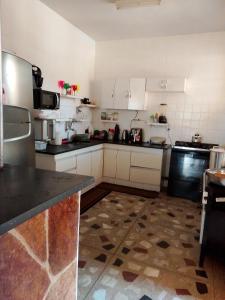 a kitchen with white cabinets and black counter tops at Quarto com varanda em casa próxima a área hospitalar em BH in Belo Horizonte +3 photos