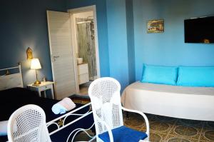 a bedroom with a bed and two white chairs at B&B A Due Passi Dal Mare in Taormina