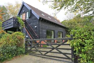 a black house with a wooden gate in front of it at Owl Lodge in Ufford +10 photos