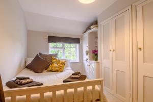 ein Schlafzimmer mit einem Bett mit Kissen und einem Fenster in der Unterkunft Riverside Cottage in Snape