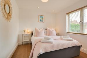 BodhamにあるDenbury Houseのベッドルーム1室(ピンクのシーツが備わるベッド2台、窓付)