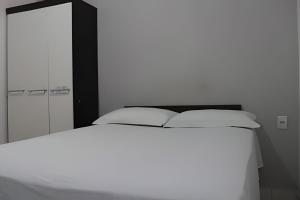 a bedroom with a white bed and a mirror at Temporada Cuiabana in Cuiabá