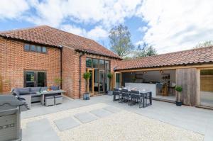 a patio with tables and chairs and a building at The Granary in Banningham
