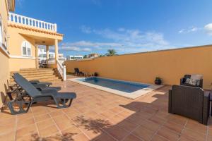 Un patio con sillas y una piscina. en Villa Veneguera + Seaview + Pool + Garden, en Maspalomas