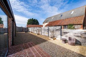 un patio al aire libre con una valla y un edificio en The Cattle Shed, en Wighton 22 fotos más