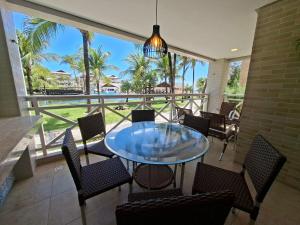 a patio with a glass table and chairs on a balcony at Apto 3 quartos Portamaris Pé na Areia Porto das Dunas in Aquiraz