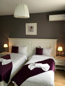two beds in a hotel room with white and purple at Avenue in Shumen +18 photos
