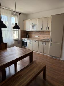 a kitchen with white cabinets and a wooden table at CosyCentrumFlat in Slezská Ostrava