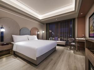 a bedroom with a large white bed and a living room at Mercure Suzhou HSR New Town in Suzhou
