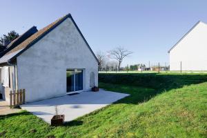 a small white building on a grassy field at La Maison à Côté - 6 couchages in Monnaie