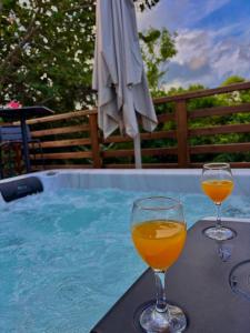 two wine glasses sitting on a table next to a swimming pool at La pause verte bungalow in Sainte-Anne